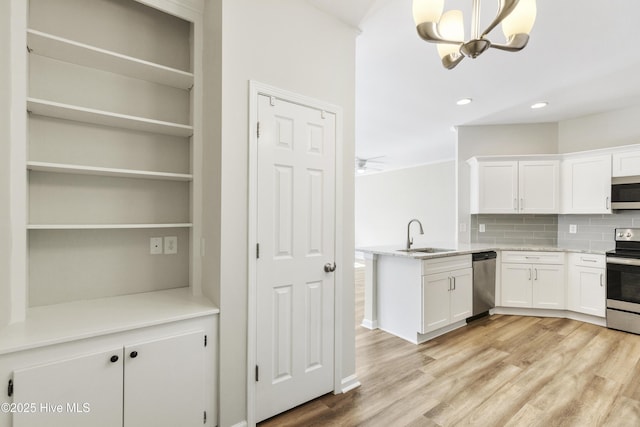 1010 Winterberry Cir, Leland, NC 28451 - kitchen featuring appliances with stainless steel finishes, a sink, white cabinetry, backsplash, and a peninsula