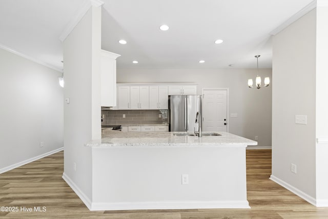 kitchen with stainless steel refrigerator with ice dispenser, a sink, light stone counters, and white cabinets