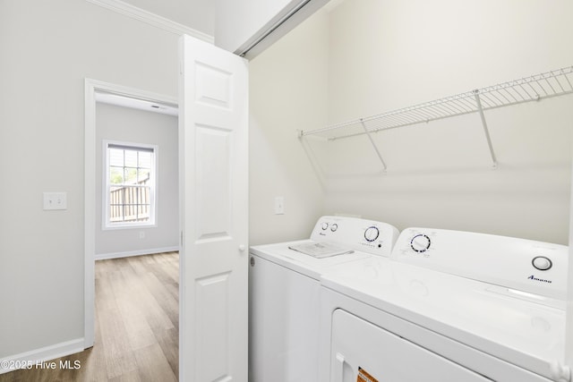 washroom with baseboards, laundry area, light wood finished floors, and washing machine and clothes dryer