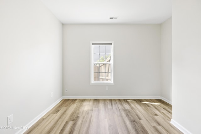 spare room featuring baseboards, visible vents, and wood finished floors