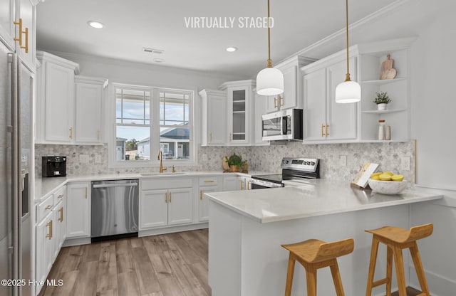 kitchen featuring open shelves, visible vents, appliances with stainless steel finishes, a sink, and a peninsula