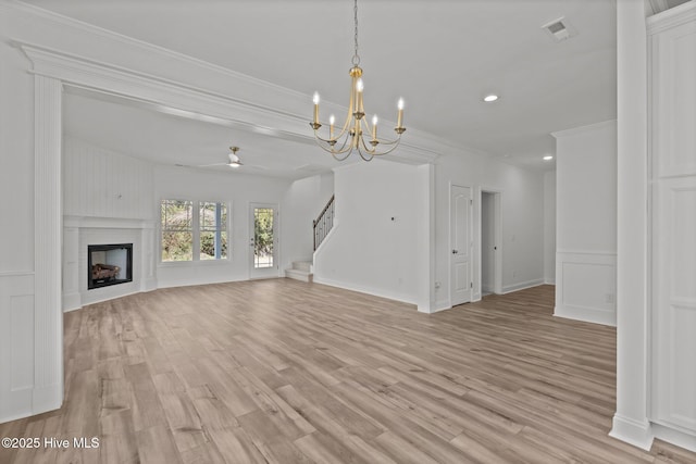 unfurnished living room with a fireplace, visible vents, light wood-style flooring, stairway, and ornamental molding