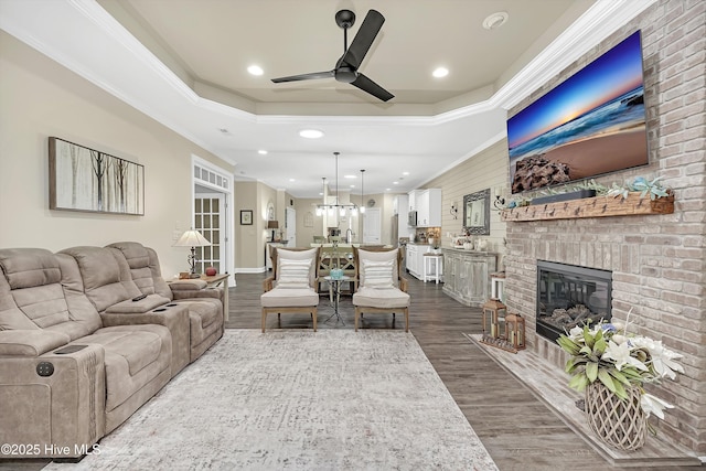 living room with crown molding, a fireplace, dark hardwood / wood-style floors, and a raised ceiling