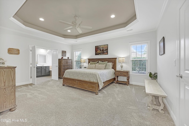 carpeted bedroom featuring ornamental molding, connected bathroom, ceiling fan, and a tray ceiling