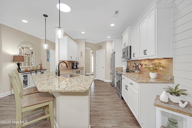 kitchen featuring sink, white cabinetry, appliances with stainless steel finishes, kitchen peninsula, and pendant lighting