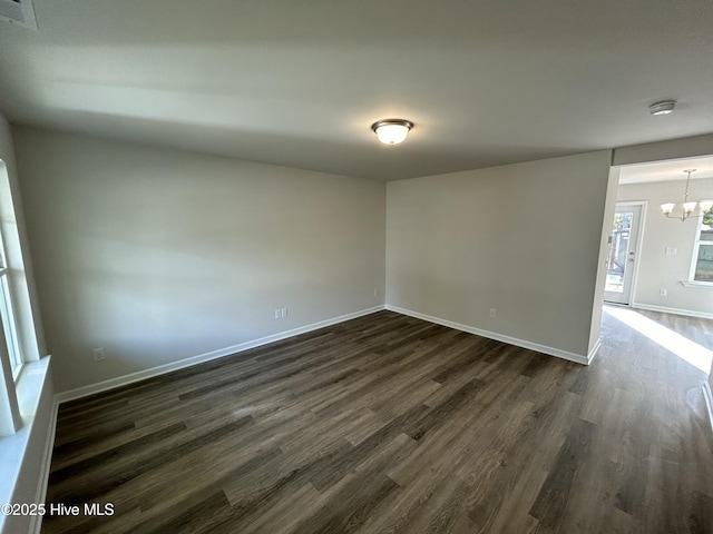 unfurnished room with dark wood-type flooring and a notable chandelier