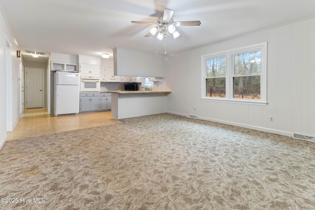 kitchen with white cabinetry, kitchen peninsula, light colored carpet, white appliances, and ceiling fan