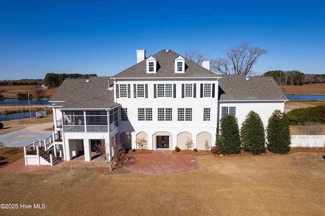 rear view of property with a sunroom and a lawn