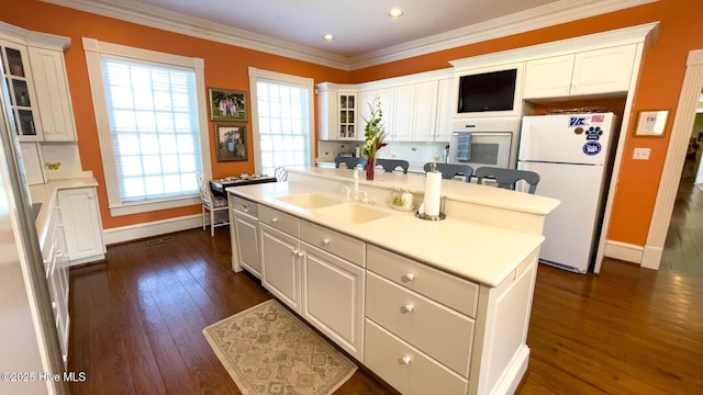 kitchen with sink, a center island with sink, white refrigerator, dark hardwood / wood-style flooring, and white cabinets