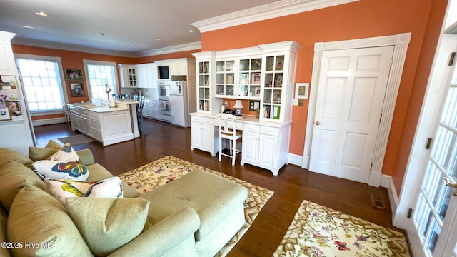 living room with dark hardwood / wood-style flooring, built in desk, and ornamental molding