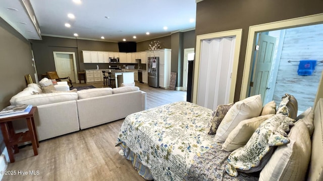 bedroom with stainless steel refrigerator, ornamental molding, and light hardwood / wood-style floors