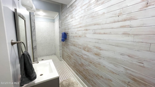 bathroom with vanity, tiled shower, and wood walls