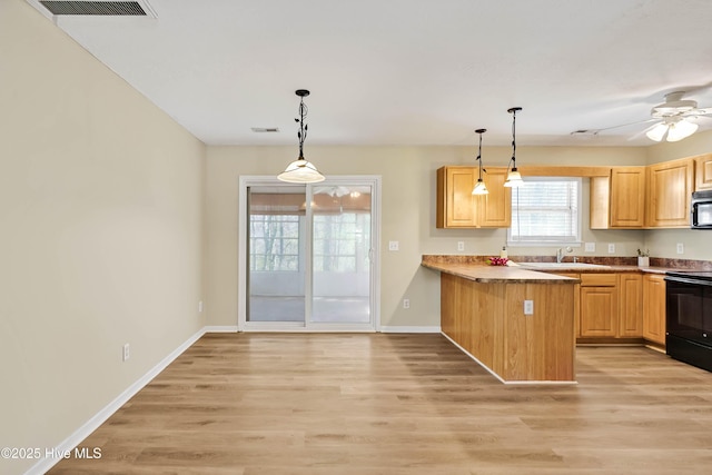 kitchen with visible vents, hanging light fixtures, black range with electric cooktop, stainless steel microwave, and light wood-type flooring