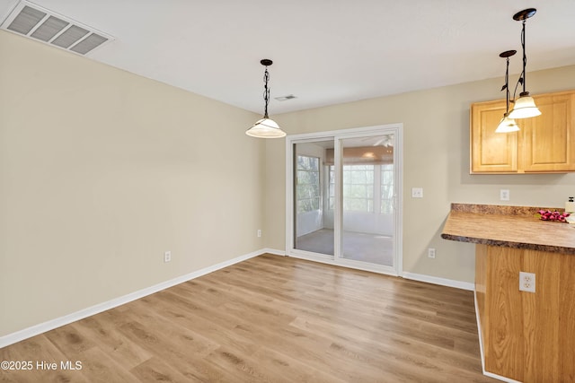 unfurnished dining area featuring baseboards, visible vents, and light wood-type flooring