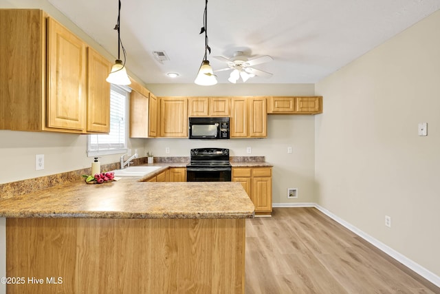 kitchen featuring light brown cabinets, baseboards, a peninsula, a sink, and black appliances