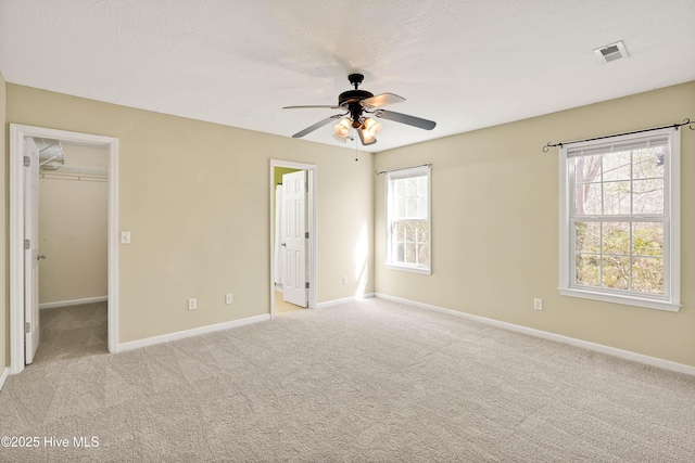 unfurnished bedroom with visible vents, ensuite bathroom, baseboards, light colored carpet, and a spacious closet