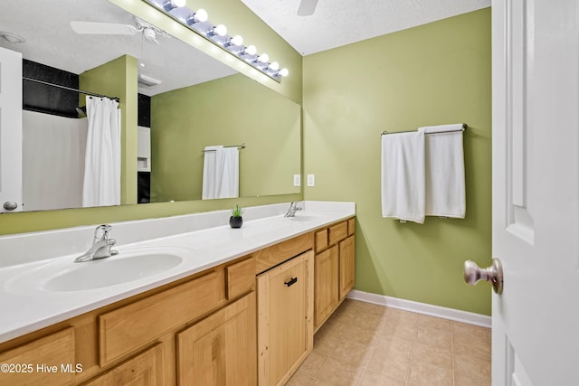 full bath with a ceiling fan, double vanity, a sink, tile patterned flooring, and a textured ceiling