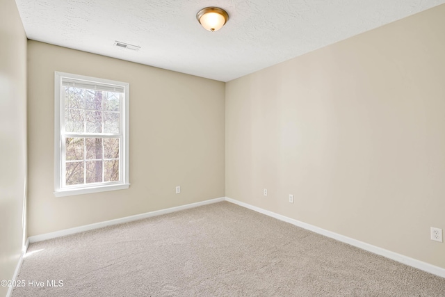 empty room featuring visible vents, baseboards, carpet floors, and a textured ceiling