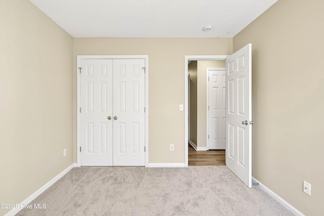 unfurnished bedroom featuring a closet, baseboards, and carpet flooring