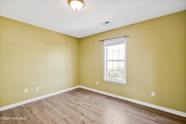 spare room with visible vents, baseboards, a textured ceiling, and wood finished floors