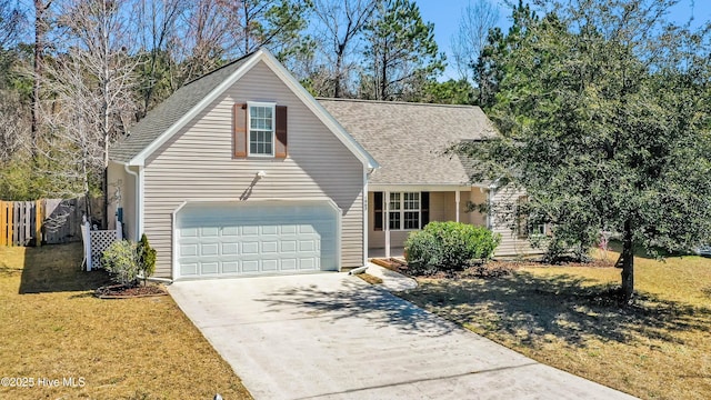 traditional-style house with a front lawn, fence, concrete driveway, roof with shingles, and a garage