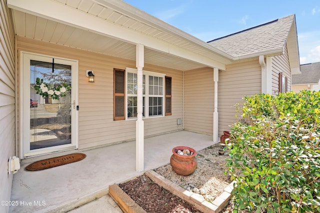 entrance to property featuring roof with shingles