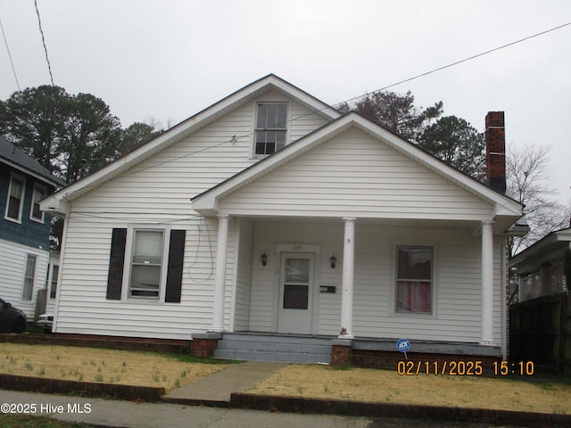 bungalow featuring covered porch and a front yard