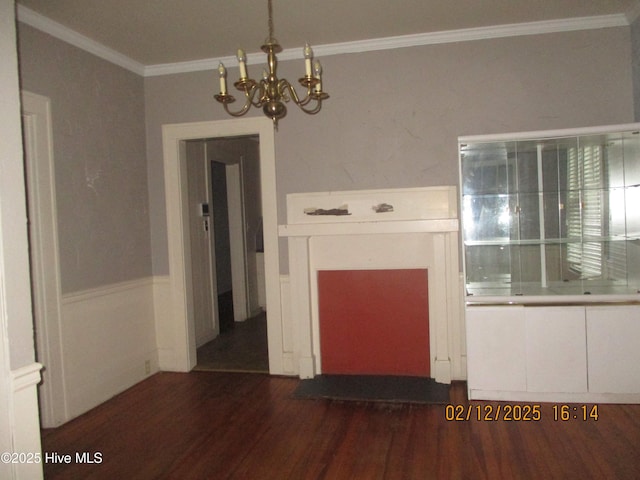 unfurnished room featuring an inviting chandelier, crown molding, a fireplace, and dark hardwood / wood-style floors