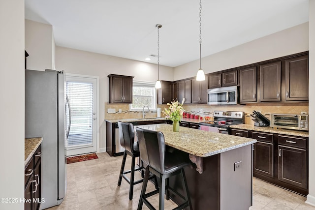 2306 Cottagefield Ln, Leland, NC 28451 - kitchen featuring appliances with stainless steel finishes, dark brown cabinets, decorative light fixtures, a kitchen island, and sink