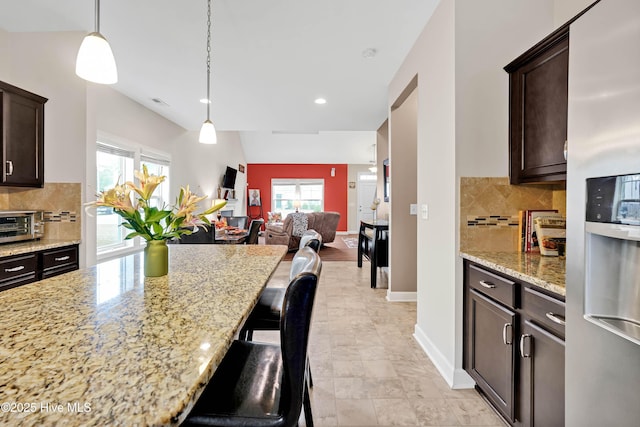 2306 Cottagefield Ln, Leland, NC 28451 - kitchen with dark brown cabinets, a kitchen bar, light stone countertops, and stainless steel refrigerator with ice dispenser