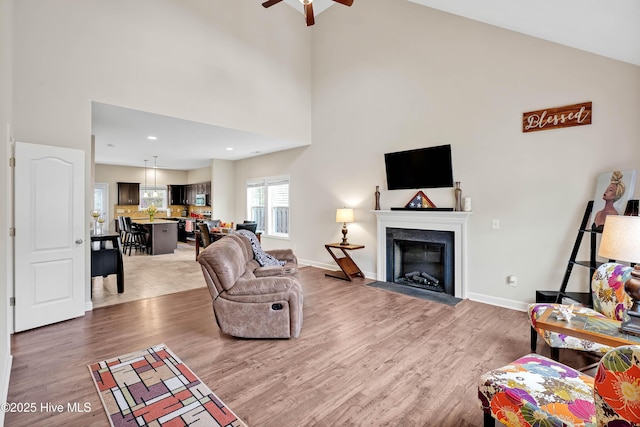 living room with hardwood / wood-style flooring, high vaulted ceiling, and ceiling fan