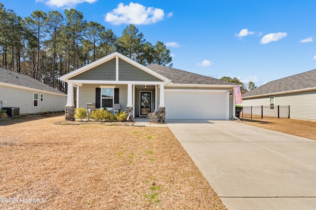 craftsman house with central AC unit, an attached garage, covered porch, fence, and concrete driveway