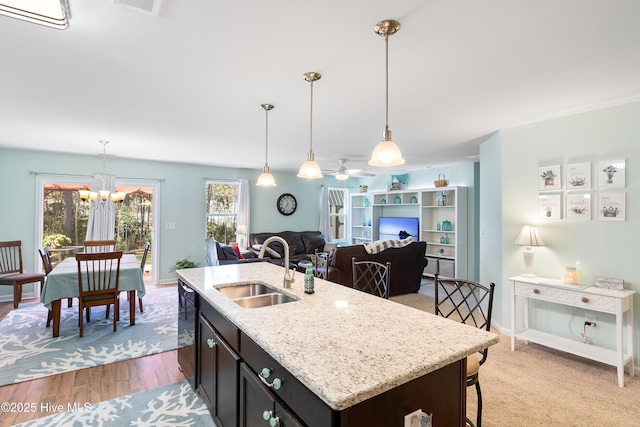 kitchen with decorative light fixtures, a sink, dishwasher, and light stone countertops