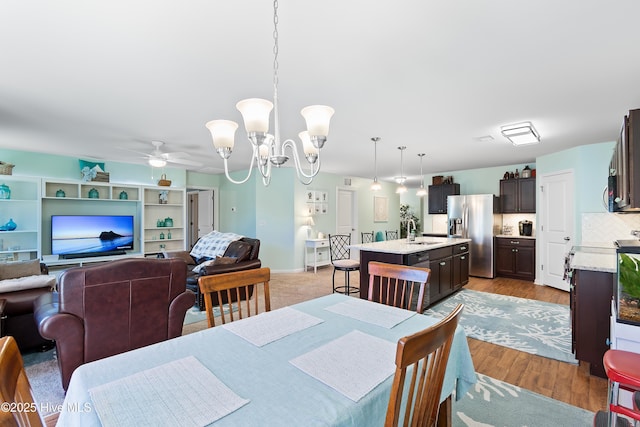 dining room with light wood-style flooring and ceiling fan with notable chandelier