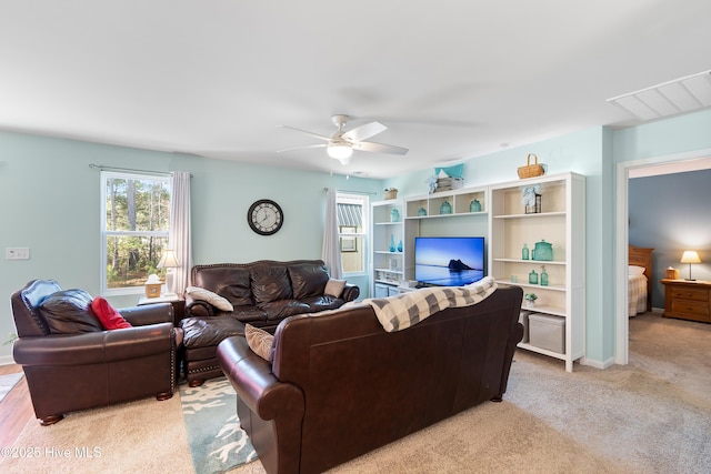 living room featuring light carpet, visible vents, and a ceiling fan