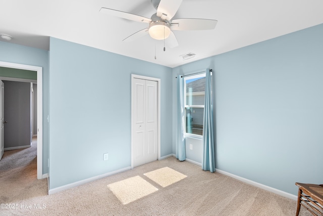 unfurnished bedroom with a closet, visible vents, a ceiling fan, light carpet, and baseboards