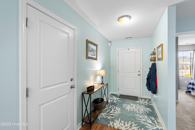 carpeted entrance foyer featuring visible vents and baseboards