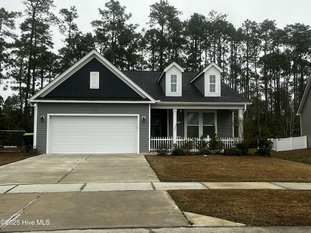 view of front of house with a porch, concrete driveway, roof with shingles, and a garage