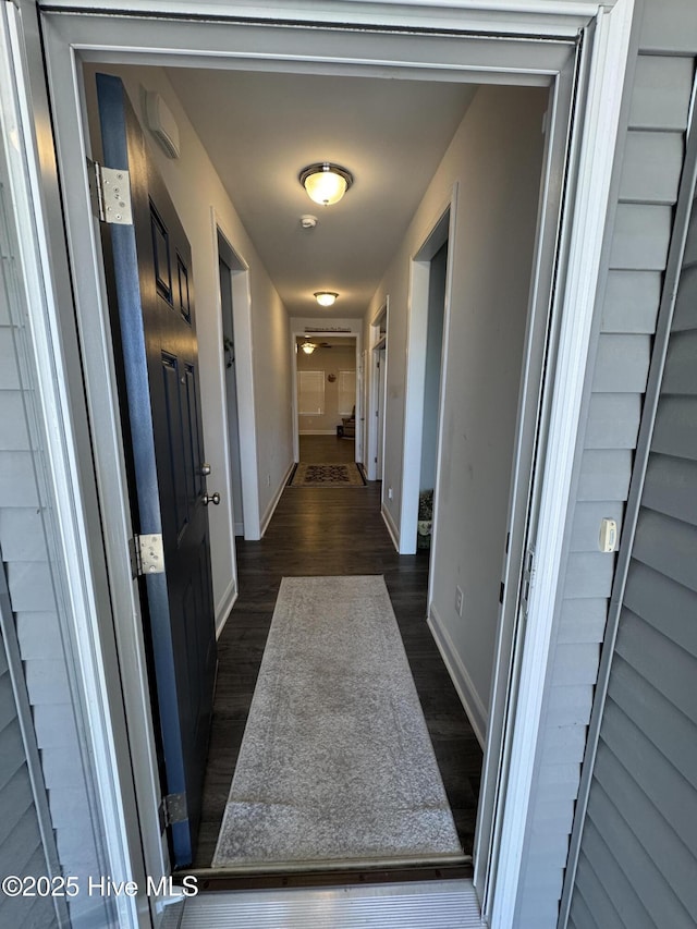 hallway featuring baseboards and dark wood-style flooring