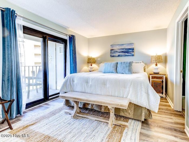 bedroom with access to outside, baseboards, light wood-style flooring, and a textured ceiling