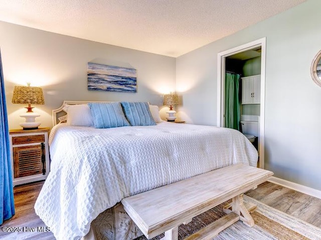 bedroom featuring a textured ceiling, baseboards, and wood finished floors