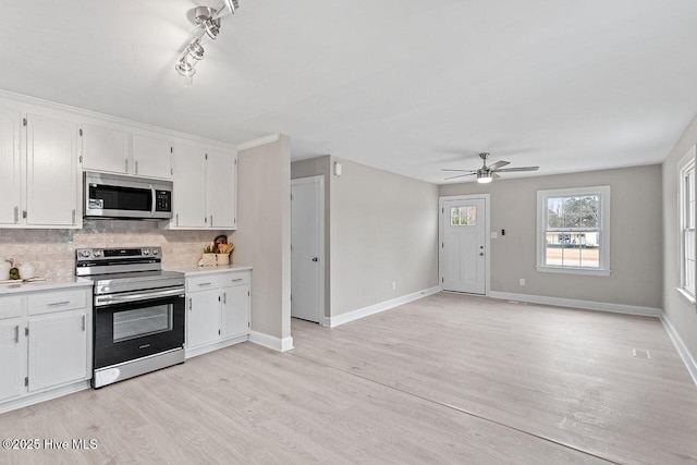 kitchen featuring white cabinetry, stainless steel appliances, decorative backsplash, and light wood-type flooring