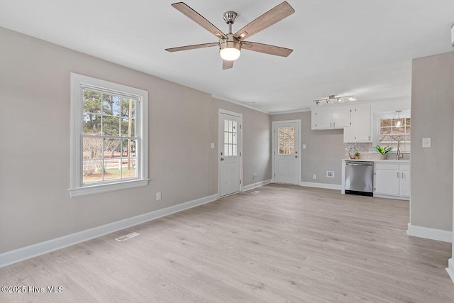 unfurnished living room featuring a healthy amount of sunlight, ceiling fan, and light hardwood / wood-style flooring