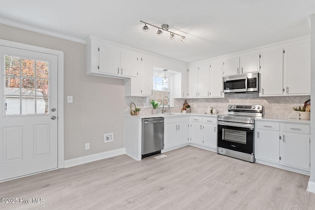 kitchen featuring ornamental molding, appliances with stainless steel finishes, and white cabinets