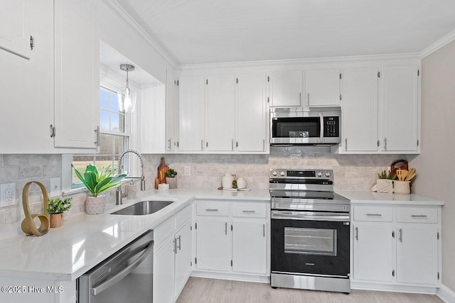 kitchen featuring sink, white cabinetry, hanging light fixtures, stainless steel appliances, and backsplash