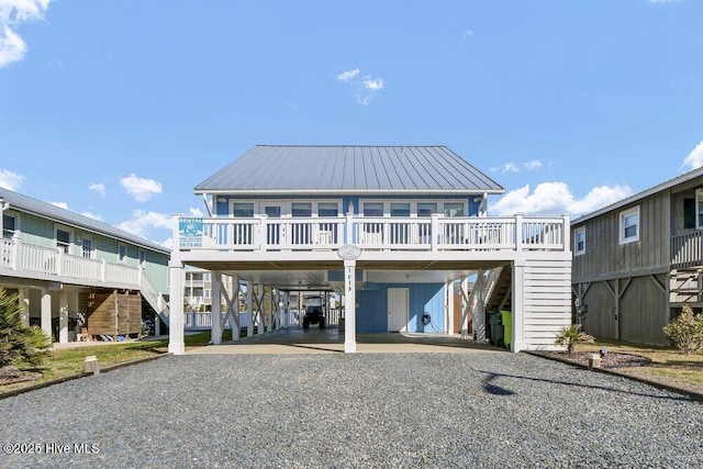 rear view of property featuring metal roof, gravel driveway, and a carport