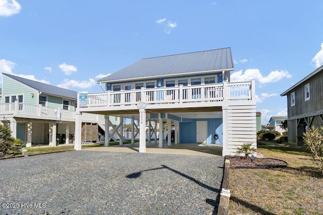 back of house with stairway, metal roof, gravel driveway, and a carport