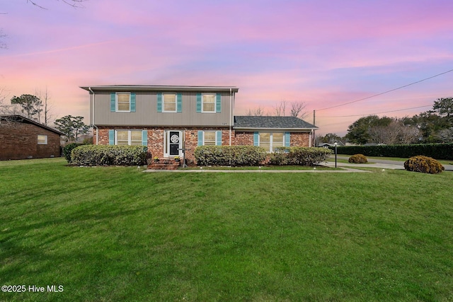 colonial inspired home featuring a yard and brick siding