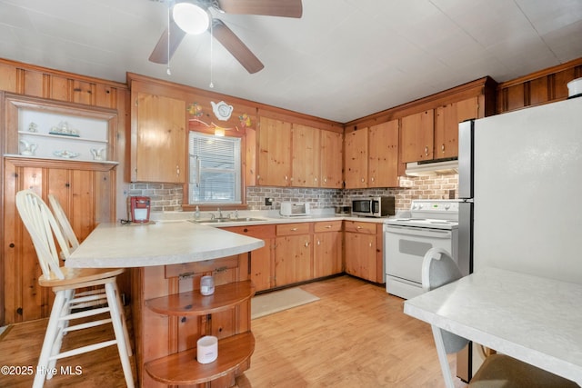 kitchen featuring light wood-type flooring, fridge, electric range, kitchen peninsula, and backsplash