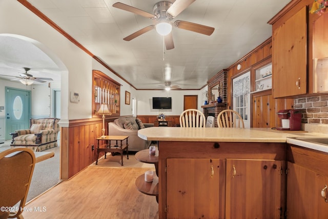 kitchen featuring crown molding, ceiling fan, kitchen peninsula, and light hardwood / wood-style flooring